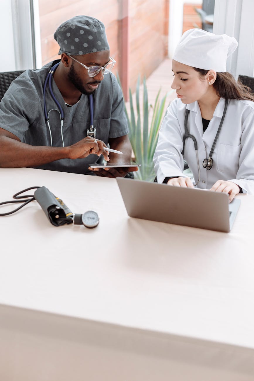 Two clinicians reviewing records together on a tablet at a desk.